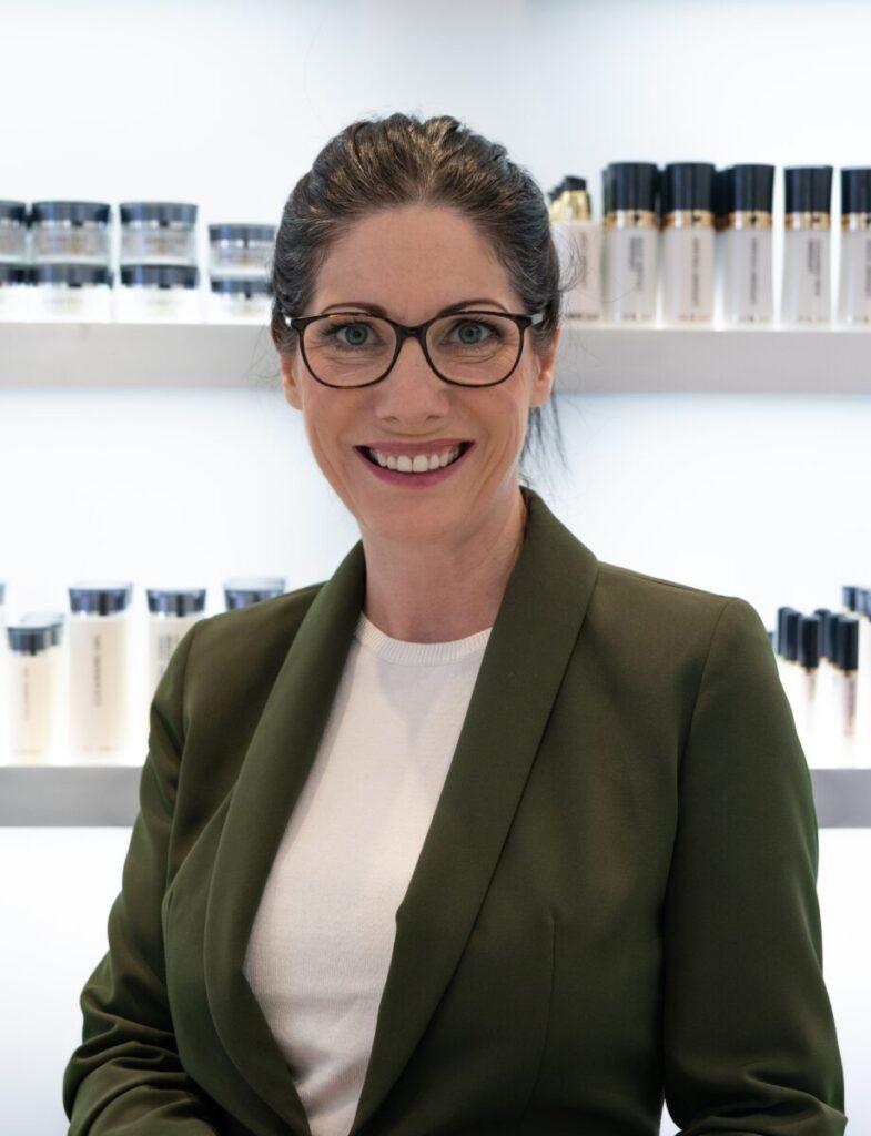 Professionelle Frau in einem Kosmetikstudio mit Gesichtscremes im Hintergrund