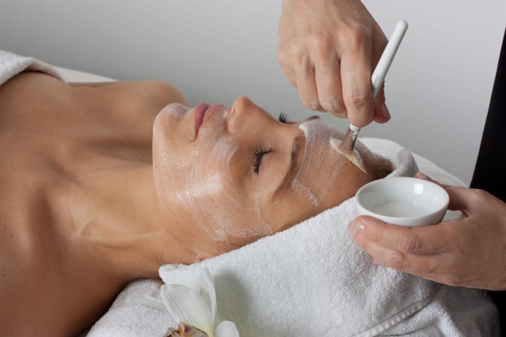 Frau erhält Gesichtsbehandlung mit Maske im Wellnessbereich